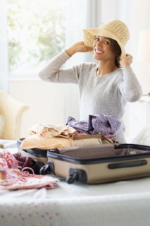 Mixed race woman packing suitcase in bed