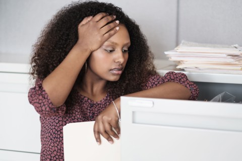 Black businesswoman searching in filing cabinet