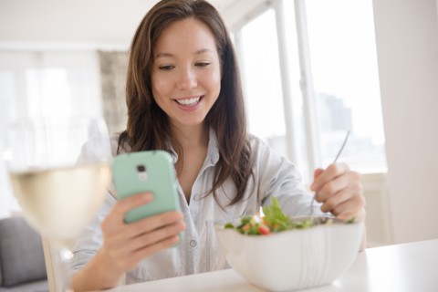 Mixed race woman photographing salad