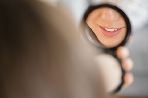 Mixed race woman admiring herself in compact mirror