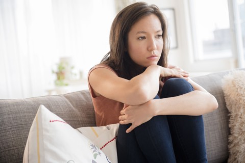 Sad mixed race woman sitting on sofa