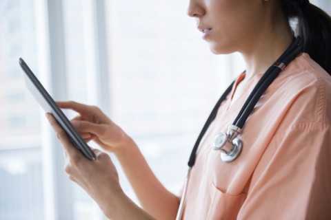 Mixed race nurse using digital tablet