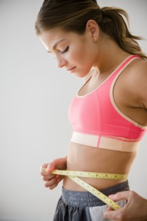Mixed race woman measuring her waist