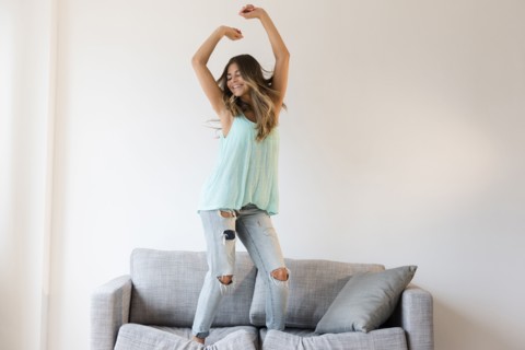 Mixed race woman jumping on sofa