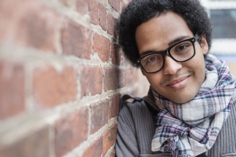 Mixed race man leaning on brick wall