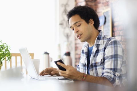 Mixed race man multitasking in coffee shop