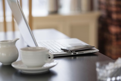 Cell phone and laptop on coffee shop table