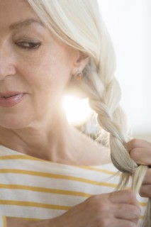 Caucasian woman braiding her hair