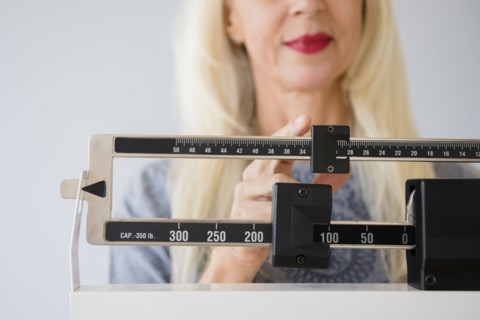 Caucasian woman weighing herself on scale