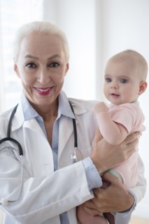 Caucasian pediatrician holding baby patient