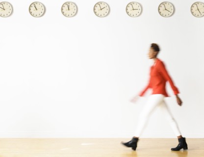 Mixed race businesswoman walking under clocks