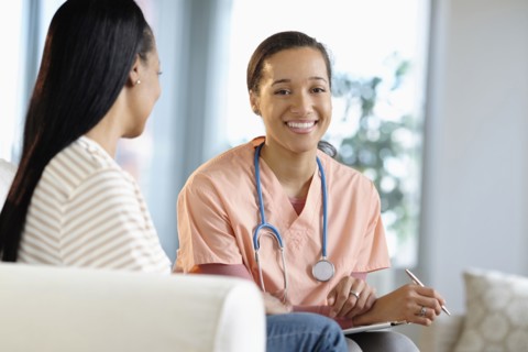 Nurse smiling with patient in living room