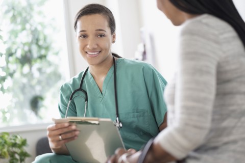Nurse with clipboard sitting with patient