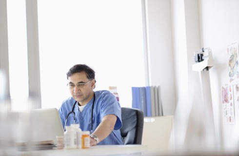 Mixed race doctor working on laptop