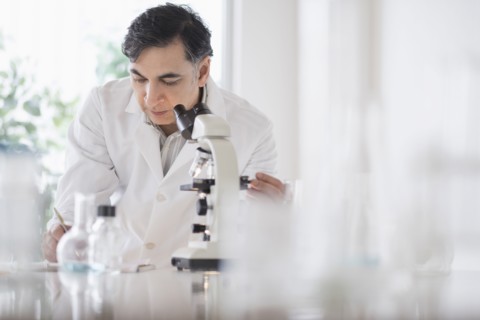 Mixed race scientist using microscope in laboratory