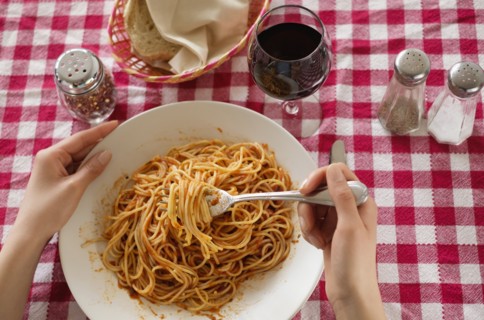 Hispanic woman eating plate of pasta