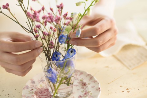Hispanic woman arranging flowers in glass cup