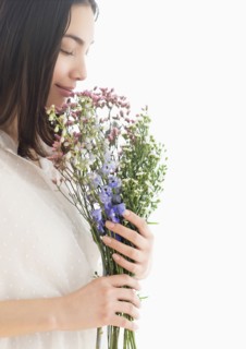Hispanic woman smelling bouquet of flowers