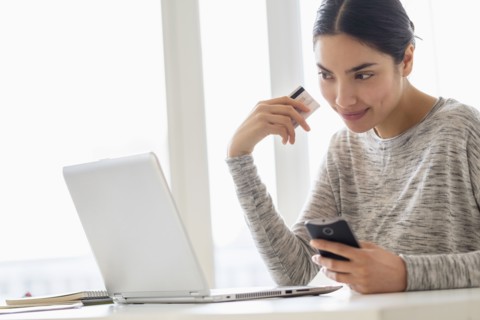 Hispanic woman shopping on cell phone and laptop