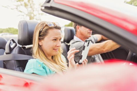 Caucasian woman using cell phone in convertible