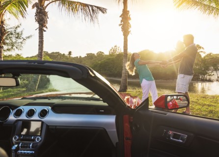 Caucasian couple dancing near convertible