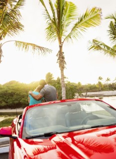 Caucasian couple hugging on convertible