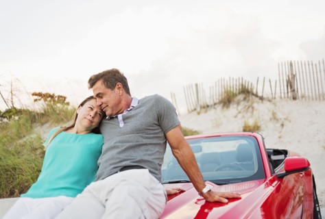 Caucasian couple sitting on convertible