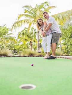 Caucasian couple playing miniature golf