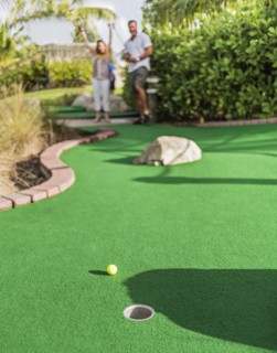 Caucasian couple playing miniature golf