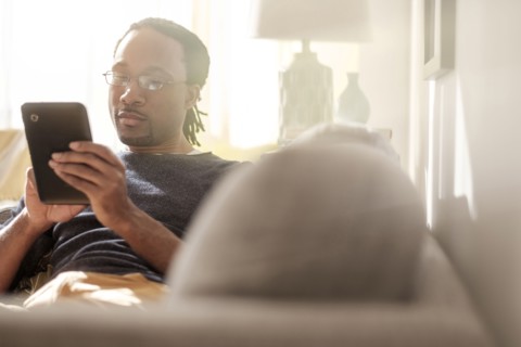 Black man using digital tablet on sofa