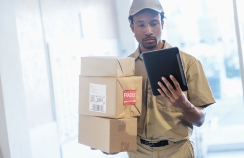 Black delivery man using digital tablet