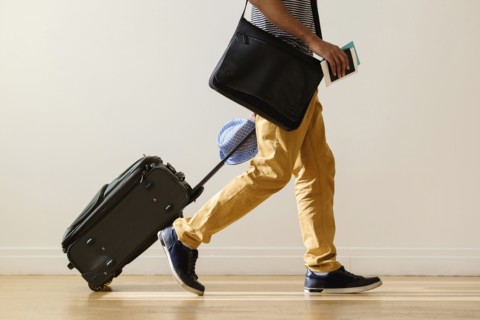 Black businessman rolling luggage