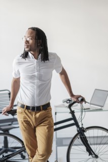 Black businessman with bicycle in office