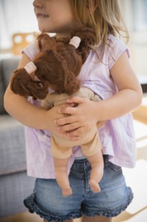 Caucasian girl hugging doll