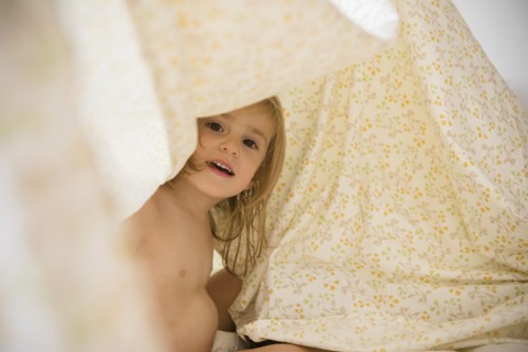 Caucasian girl playing under blankets