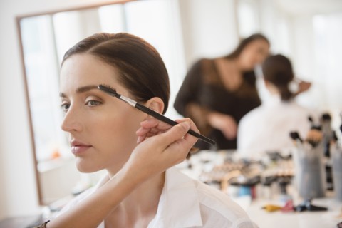 Woman having makeup applied by stylist
