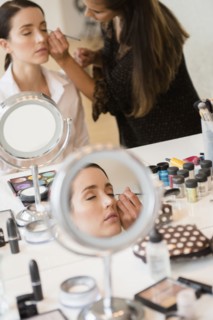 Woman having makeup applied by stylist