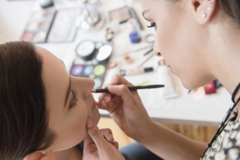 Woman having makeup applied by stylist