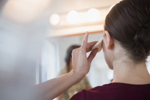 Woman having makeup applied by stylist