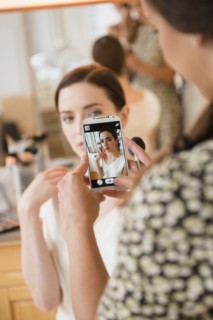 Makeup artist photographing client with cell phone