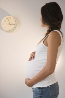 Pregnant Caucasian woman watching clock