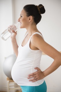 Pregnant Caucasian woman drinking water bottle