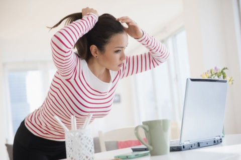 Woman styling her hair with laptop
