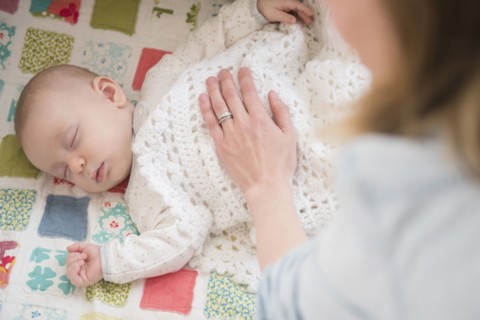 Caucasian mother checking on sleeping baby