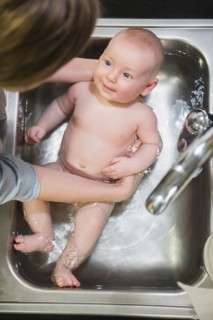 Caucasian mother bathing baby in sink