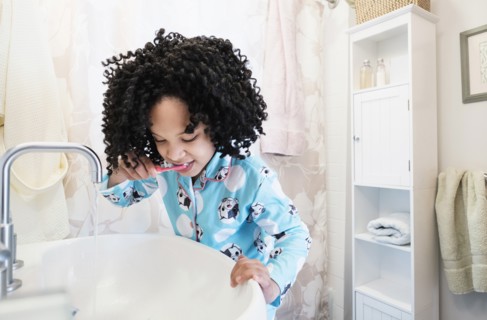 African American girl brushing teeth in bathroom