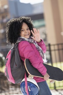 African American girl carrying skateboard outdoors