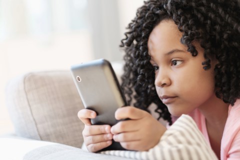 African American girl using cell phone on sofa