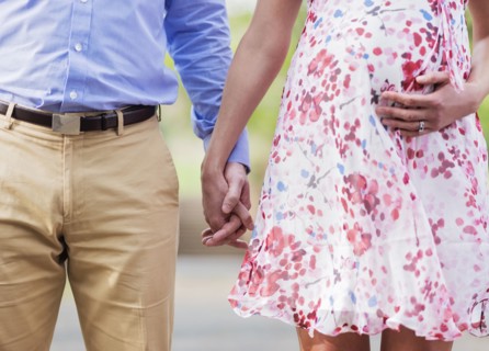 Pregnant Caucasian couple holding hands outdoors