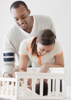 African couple looking at baby in crib